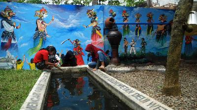 Anak-anak bermain air di sekitar instalasi penjernih air yang merupakan bagian dari instalasi seni berjudul Mata Air Baru karya Tisna Sanjaya, di halaman Galeri Ibu Cigondewah, Bandung, 22 Desember 2021. TEMPO/Prima Mulia