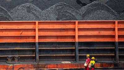 Pekerja melintas di dekat kapal tongkang pengangkut batubara di kawasan Dermaga Batu bara Kertapati milik PT Bukit Asam Tbk di Palembang, Sumatera Selatan, 4 Januari 2022. ANTARA/Nova Wahyudi