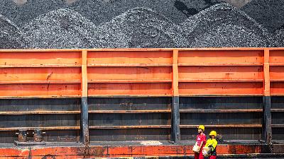 Workers walk pass a barge transporting coal at the Kertapati Coal Pier area of Bukit Asam in Palembang, South Sumatra, January 4. The government requires private companies, state-owned enterprises and their mining subsidiaries to prioritize domestic needs of coal.
ANTARA FOTO/Nova Wahyudi

