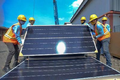 Pekerja melakukan pemasangan panel surya di pabrik Coca-Cola Amatil Indonesia, Cibitung, Bekasi, Jawa Barat, 2 Desember 2021. Tempo/Tony Hartawan