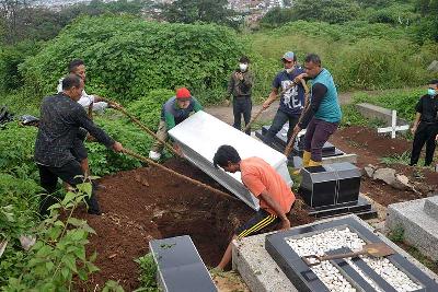 Petugas memasukan peti tanpa perlindungan APD saat pemakaman jenazah dengan hasil tes positif di pemakaman khusus Covid-19 Cikadut, Bandung, Jawa Barat, 10 Februari 2022. TEMPO/Prima Mulia