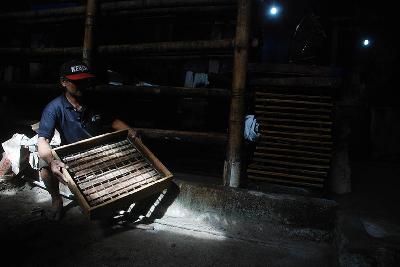 Pekerja memegang alat produksi saat mogok di sentra industri tahu Cibuntu, Bandung, Jawa Barat, 21 Februari 2022. Sejumlah pabrik tahu dan tempe melakukan mogok produksi terkait melambungnya harga kedelai impor. TEMPO/Prima Mulia