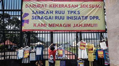 Massa yang tergabung dalam Jaringan Pembela Hak Perempuan Korban Kekerasan Seksual memasang instalasi baju korban kekerasan seksual saat melakukan aksi unjuk rasa di depan Gedung DPR, Jakarta, Rabu, 22 Desember 2021. TEMPO/M Taufan Rengganis