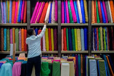 Pekerja toko tengah merapikan kain yang dijual di Pasar Baru, Jakarta. Tempo/Tony Hartawan