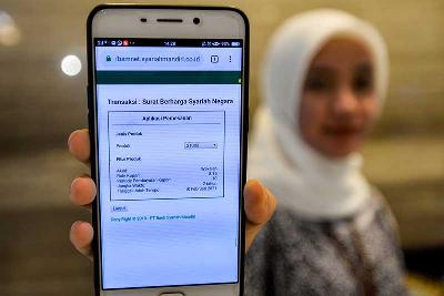 Nasabah melakukan transaksi pembelian Surat Berharga Syariah Negara pada aplikasi perbankan di Bank Mandiri Syariah, Jakarta. TEMPO/Tony Hartawan