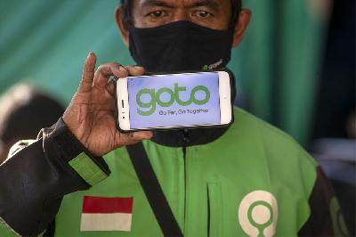 Mitra layanan ojek daring Gojek menunjukkan logo merger perusahaan Gojek dan Tokopedia di shelter penumpang Stasiun Kereta Api Sudirman, Jakarta. ANTARA/Aditya Pradana Putra