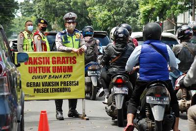 Pengendara sepeda motor melewati pusat vaksinasi Covid-19 untuk mendapat booster vaksin AstraZeneca di Polsek Lengkong, Bandung, 8 April 2022.  TEMPO/Prima Mulia
