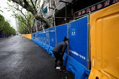 Seorang warga Shanghai membeli makanan melalui lubang barikade pada pemberlakuan lock down penyebarang COVID-19 di Cina, 14 April 2022. REUTERS / Aly Song