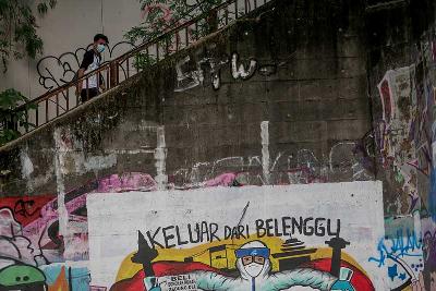 Warga melintasi mural bertema Covid-19 di Bidara Cina, Jakarta, 11 Mei 2022. Tempo/Hilman Fathurrahman W