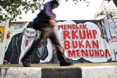 Warga melintas di dekat mural penolakan Rancangan Kitab Undang-Undang Hukum Pidana (KUHP) di Rawamangun, Jakarta, 28 September 2019. TEMPO/ Hilman Fathurrahman W