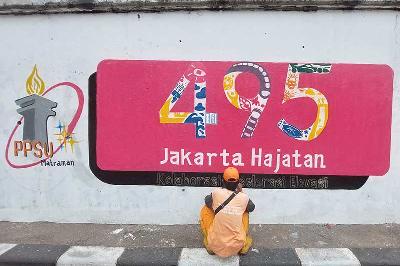 Petugas PPSU menyelesaikan pembuatan mural dengan tema Hari Ulang Tahun DKI Jakarta di Matraman, Jakarta, 14 Juni 2022. TEMPO/Muhammad Hidayat