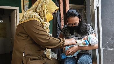 A midwife from a Community Health Center examines a mother and her baby at the Anggrek 2 Integrated Health Service Post, Depok, West Java, October 2021.
TEMPO/M Taufan Rengganis
