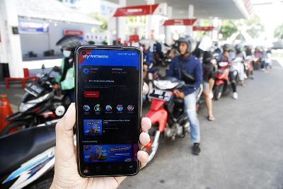 Pengendara sepeda motor menunjukan aplikasi MyPertamina dekat antrean BBM Pertalite di SPBU Pertamina Jalan RE Martadinata, Bandung, Jawa Barat, 29 Juni 2022. TEMPO/Prima Mulia