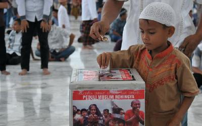 Anak memasukan uang ke dalam kotak amal Peduli Muslim Rohingya di Masjid Raya Baiturrahman, Aceh, 2017. ANTARA/Ampelsa