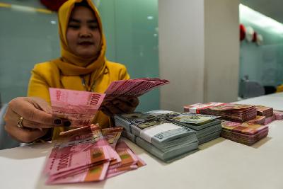 Pegawai bank menghitung uang rupiah pecahan 100 ribu di kantor pusat Bank Mandiri, Jakarta. TEMPO/Tony Hartawan