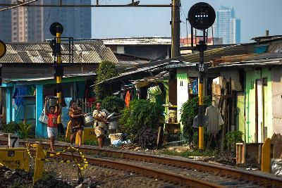 Warga berjalan di depan rumah mereka di pinggiran rel kereta kawasan Kampung Bandan, Jakarta, 30 Juni 2022. TEMPO/Tony Hartawan