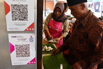 Pedagang menyiapkan sajian makanan di sebuah stan yang telah melayani pembayaran dengan metode scan Quick Response Code Indonesian Standard (QRIS) di Jawa Timur, 19 Agustus 2022. ANTARA/Siswowidodo