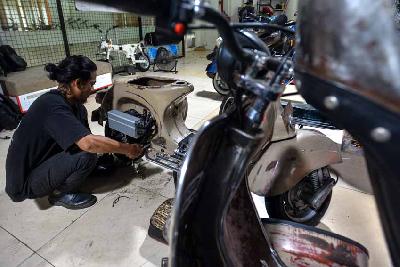 Pekerja menyelesaikan konversi mesin motor listrik Vespa di Elders Garage, Jakarta, 23 Agustus 2022. Tempo/Tony Hartawan