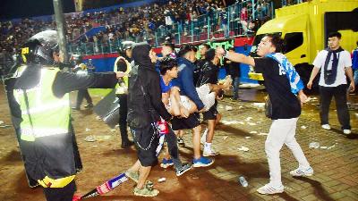 Suporter mengevakuasi seorang pria akibat gas air mata yang ditembakkan polisi usai pertandingan sepak bola Arema vs Persebaya di Stadion Kanjuruhan, Malang, Provinsi Jawa Timur, 1 Oktober 2022/REUTERS/Stringer 