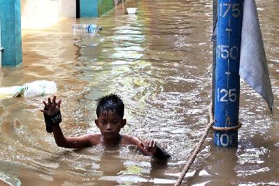 Anak-anak berjalan melintasi banjir di Bidara Cina, Jakarta, 10 Oktober 2022. ANTARA/Henry Purba