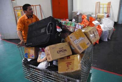 Pegawai PT Pos Indonesia memindahkan sejumlah paket barang  di Kantor Pos Pusat Kota Malang, Jawa Timur. Dokumkentasi TEMPO/Aris Novia Hidayat