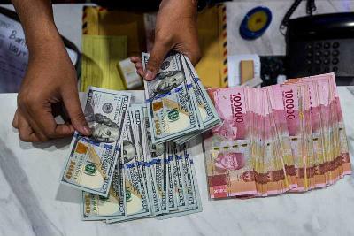 Petugas menghitung uang pecahan 100 dolar Amerika dan uang pecahan Rp100 ribu di Jakarta, 6 Desember 2021. Tempo/Tony Hartawan
