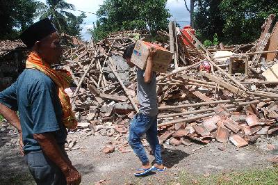 Warga membawa logistik di depan rumah yang rusak akibat gempa di Kampung Selakawung,  Cilaku, Cianjur, Jawa Barat, 22 November 2022. TEMPO/Prima mulia