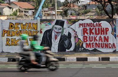 Pengendara melintas di dekat mural penolakan terhadap RKUHP di Jalan Pemuda, Rawamangun, Jakarta, 28 September 2019. TEMPO / Hilman Fathurrahman W