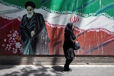 Seorang wanita berjalan di depan mural Pemimpin Iran Ayatollah Ruhollah Khomeini di Tehran, Iran, 2019. Nazanin Tabatabaee/WANA (West Asia News Agency) via REUTERS
