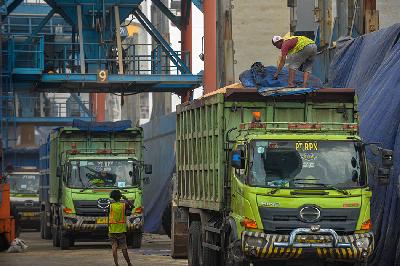 Pekerja menutup truk yang berisi gandum impor di dermaga Pelabuhan Tanjung Priok, Jakarta, 20 Desember 2022. TEMPO/Tony Hartawan