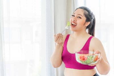 Seorang wanita makan sayuran. Shutterstock