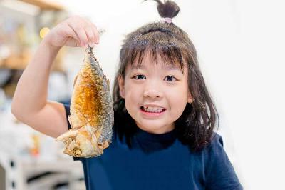 Seorang anak makan ikan. Shutterstock