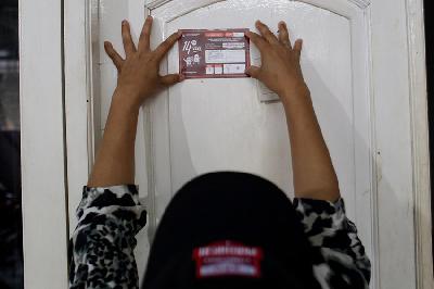 Petugas Pemutakhiran Data Pemilih (Pantarlih) menempelkan tanda lolos tahapan coklit ke rumah warga di Cisalak, Depok, Jawa Barat, 22 Februari 2023. TEMPO/M Taufan Rengganis