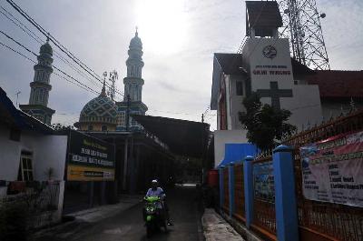 Warga melintasi jalan antara Masjid Al-Muqorrobin (kiri) yang berhadapan dengan Gereja Kristen Muria Indonesia di Desa Winong, Kota, Pati, Jawa Tengah, 30 Maret 2023. ANTARA/Yusuf Nugroho