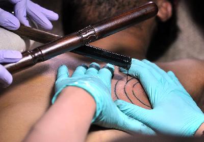 Seniman tatto, Ranu Khodir, membuat tato dengan teknik tradisional 'Hand Tapping' di Matraman, Jakarta. Dok. TEMPO/Dasril Roszandi