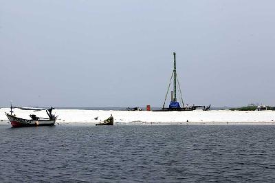 Perahu nelayan dengan latar hamparan pasir putih di lokasi reklamasi Pulau K, Ancol, Jakarta. TEMPO/Subekti