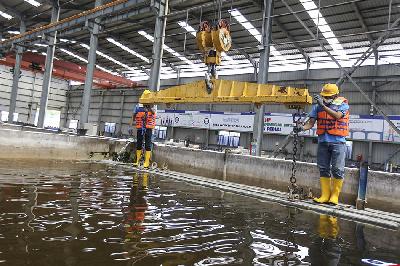 Pekerja mengangkat bantalan rel (slab track) yang direndam di dalam air di Pabrik Slab Track PT WIKA Beton, Karawang, Jawa Barat, 18 Mei 2022.  ANTARA/Asprilla Dwi Adha