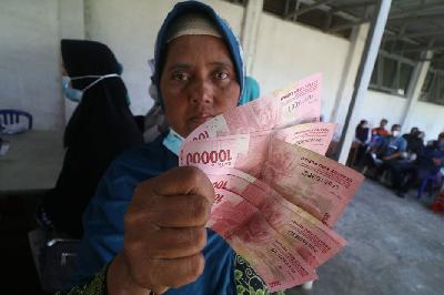 Warga penerima manfaat memperlihatkan uang tunai saat pencairan Program Keluarga Harapan (PKH) dan bantuan sosial sembako di Kantor Pos Besar Kota Kediri, Jawa Timur, 13 Mei 2023. ANTARA/Prasetia Fauzani