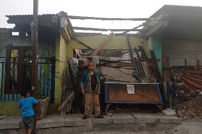 Ahmad Syukur, warga desa kampung Tanah Merah dengan latar kondisi rumah dan bekas warung bakso yang rusak pasca kebakaran, 20 Juni 2023. Tempo/Jihan Ristiyanti