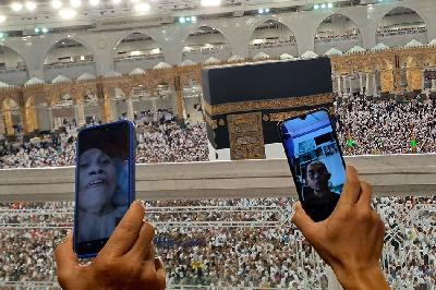 Jamaah calon haji Indonesia melakukan panggilan video dengan latar belakang Ka’bah seusai sholat subuh di Masjidil Haram, Arab Saudi, 13 Juni 2023. ANTARA/Wahyu Putro A