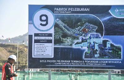 Seorang pekerja berdiri dekat poster proyek pembangunan smelter PT Amman Mineral Nusa Tenggara (AMNT) di Dusun Otak Keris, Maluk, Sumbawa Barat, Nusa Tenggara Barat, 20 Juni 2023. ANTARA/Ahmad Subaidi