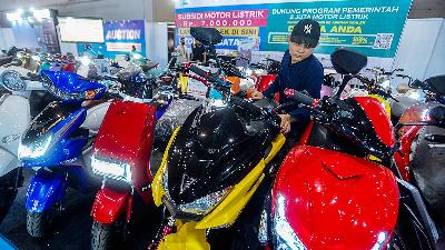 A visitor looks at electric motorcycles on display in front of a banner promoting a Rp7 million subsidy incentive for purchase of electric motorbikes, at the Periklindo Electric Vehicle Show (PEVS) 2023 in Jakarta, May 17.
Tempo/Tony Hartawan

