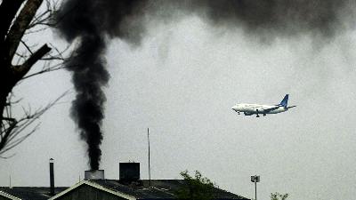 Sebuah pesawat melintas di dekat cerobong sebuah industri yang mengeluarkan asap tebal, di Bandara Soekarno-Hatta, Tangerang, Banten, 14 Desember 2007. Tempo/Imam Sukamto