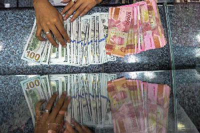 Pegawai penukaran mata uang asing menghitung uang Amerika pecahan dolar dan rupiah di Jakarta, 7 Agustus 2023. Tempo/Tony Hartawan