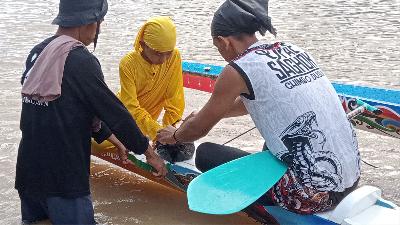Peserta dari tim Upea Shagok Gimbo Dusun membuka bungkusan berisi air dan beras yang telah diberi doa sebelum memulai perlombaan Pacu Jalur/Tempo/Dian Yuliastuti
