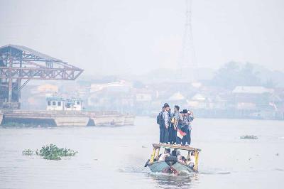 Sejumlah pelajar berangkat sekolah menggunakan perahu tradisional melewati kawasan yang diselimuti kabut asap di Sungai Ogan, Palembang, Sumatera Selatan, 6 September 2023. ANTARA/Nova Wahyudi