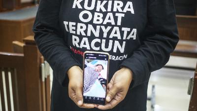 Solihah, one of the parents of progressive atypical acute kidney injury (GGAPA) victims, showing a photo of her child while attending the continued hearing of the GGAPA group’s class action lawsuit at the Central Jakarta District Court, Jakarta, July 18. 
TEMPO/Hilman Fathurrahman W
