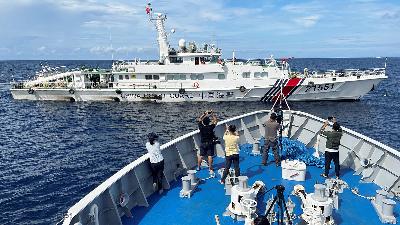 Journalists onboard a Philippines Coast Guard ship take photos of a China Coast Guard vessel during a resupply mission for troops stationed at a grounded Philippines ship in the South China Sea, September 8. 
REUTERS/Jay Ereno
