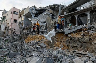 Anak-anak berdiri di atas puing-puing rumah yang hancur akibat serangan Israel, di Khan Younis di selatan Jalur Gaza, Palestina, 11 Oktober 2023. REUTERS/Ibraheem Abu Mustafa