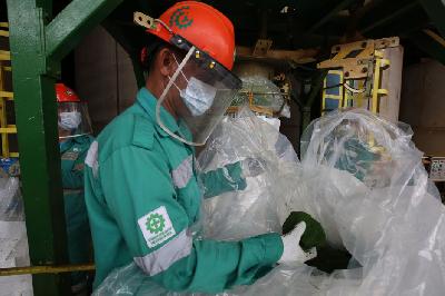 Pekerja melakukan proses pengemasan bahan baku baterai kendaraan listrik Mixed Hydroxide Precipitate (MHP) di PT Halmahera Persada Lygend, Pulau Obi, Maluku Utara, 16 Juni 2023. TEMPO/Subekti.
